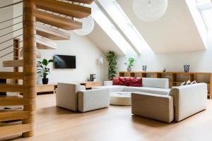 a living room with white furniture and a staircase at Roset Hotel & Residence in Bratislava