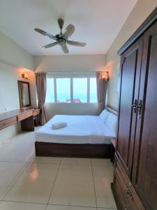 - une chambre avec un lit et un ventilateur de plafond dans l'établissement Aloka Seaview Apartment, à Batu Ferringhi