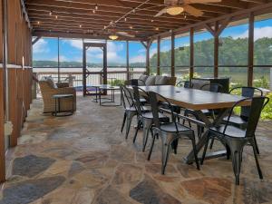 d'une terrasse avec des tables, des chaises et des fenêtres. dans l'établissement Lakefront Lodge with King Beds and Game Lounge, à Worthville
