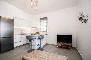 een witte keuken met een wastafel en een tv bij Anesis Town Apartments in Rhodos-stad