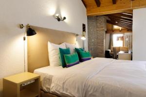 una camera da letto con un letto bianco con cuscini blu e verdi di Hôtel de l'Ange a Nyon