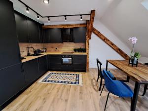 cocina con armarios negros y mesa de madera en PIASTA STREET APARTMENT, en Wałbrzych