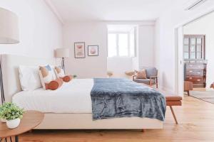 um quarto branco com uma cama grande e uma cadeira em Downtown Charming Apartments Apartamento Poldras em Chaves