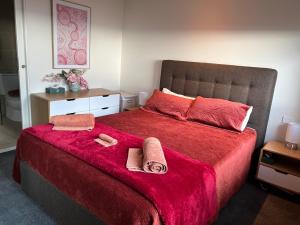 1 dormitorio con 1 cama roja y 2 toallas en Lovely 2-bedroom apartment, breathtaking view! en Frankston
