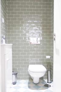 een badkamer met een wit toilet en een groene bakstenen muur bij Downtown Charming Apartments Apartamento Poldras in Chaves