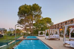 une piscine avec deux lits et un hôtel dans l'établissement Secrets Mallorca Villamil Resort & Spa - Adults Only (+18), à Paguera