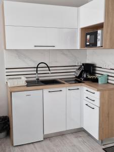 a kitchen with white cabinets and a sink at Boros Vendégház in Bogács
