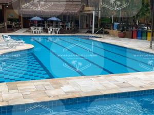 uma grande piscina com água azul em Flat Perfeito Flat Amarilis em Riviera São Lourenço com café da manhã e enxoval completo praia e piscina com trocas em Riviera de São Lourenço