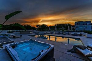 a hot tub on a patio with a sunset in the background at Luxury Villa Del Sogno with pool, jacuzzi, parking in Trogir