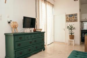 a green dresser with a television on top of it at Villager's Art Apartment in Paradeísion