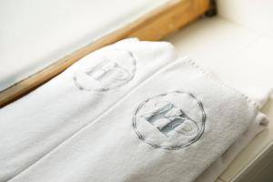 two white towels with a symbol on top of a bed at Hôtel de l'Ange in Nyon +76 photos