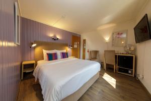 a bedroom with a large white bed and a desk at Hôtel de l'Ange in Nyon