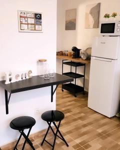 uma cozinha com uma mesa, um frigorífico e 2 bancos em Villa MIA 2.0 em Giniginámar