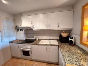 una cocina con armarios blancos y fregadero en Apartamento con vistas al mar, en Altea