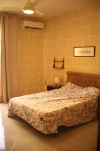 um quarto com uma cama e uma parede de tijolos amarelos em Entire apartment with Ramla Bay view (Gozo, Malta) em Il-Pergla