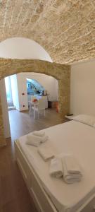 um quarto com uma cama branca e toalhas em Le case di Roberto em Gioia del Colle