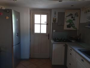 a kitchen with a white door and a window at Maison de village in Sourribes