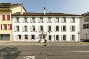 un edificio bianco con una bandiera davanti di Hôtel de l'Ange a Nyon