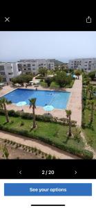 une vue d'une piscine avec des palmiers devant un immeuble dans l'établissement Appartement 3chambres avec piscine, à Agadir nʼ Aït Sa