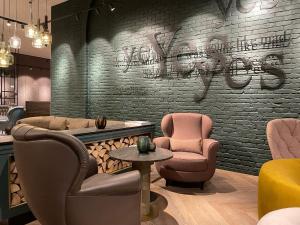 salon z 2 krzesłami i ceglaną ścianą w obiekcie Motel One Dublin w Dublinie