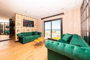 a living room with green couches and a view of the ocean at Hotel Antonio II in Zahara de los Atunes