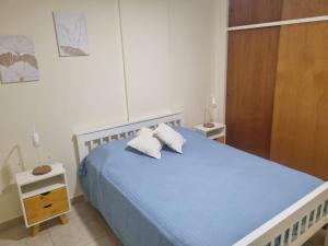 ein Schlafzimmer mit einem blauen Bett mit zwei Kissen in der Unterkunft Departamento Bahía Blanca con cochera cubierta in Bahía Blanca