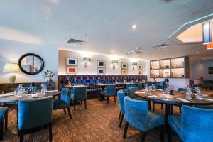 uma sala de jantar com mesas e cadeiras azuis em Wrightington Hotel & Health Club em Wigan