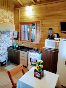 a kitchen with a refrigerator and a table in a room at Hindu Box Containers e Cabanas in Praia do Rosa