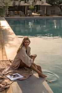 Eine Frau, die auf einem Handtuch neben einem Pool sitzt. in der Unterkunft Cook's Club Kolymbia Rhodes -Adults only in Kolymbia