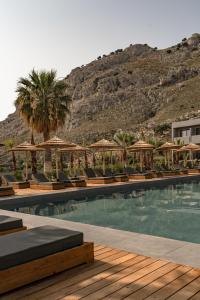a swimming pool with chairs and a mountain in the background at Cook's Club Kolymbia Rhodes -Adults only in Kolimbia