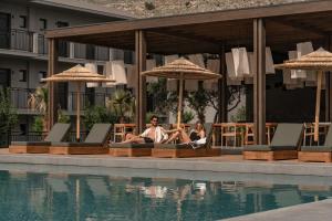 two people sitting on lounge chairs next to a swimming pool at Cook's Club Kolymbia Rhodes -Adults only in Kolymbia