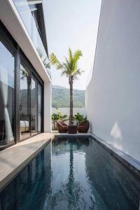 een zwembad naast een huis met een palmboom bij Monkey Mountain Villa Retreat 1 in Da Nang