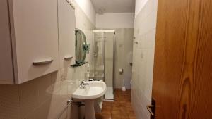 a white bathroom with a sink and a shower at Appartamento Valentina in Levico Terme