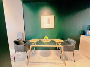 a table and chairs in a room with a green wall at Studio Staycation D'Sara @ Linked MRT, Near Thomson Hospital & Sungai Buloh Hospital in Sungai Buluh