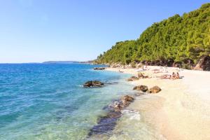 a beach with people laying on the sand and the water at Epetium Beach Villa in Split