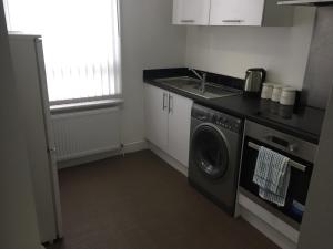 a kitchen with a washing machine and a sink at Alphalink Apartment in Middlesbrough