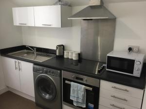 a kitchen with a microwave and a washer and dryer at Alphalink Apartment in Middlesbrough