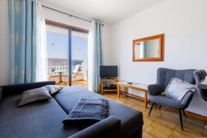 a bedroom with a couch and a chair and a window at Apartmento Cactus II in Los Cristianos