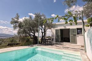 a swimming pool in front of a house at Admonis - Home in the olive grove in Melissátika
