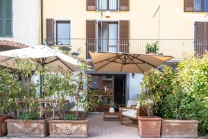 un patio con piante e ombrelloni di fronte a un edificio di La Lupa La Morra a La Morra