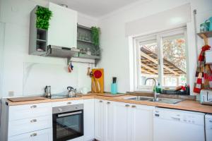 a kitchen with white cabinets and a sink and a window at Moby Dick Lodge Colares in Sintra