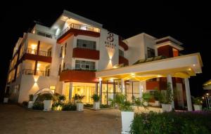 a large white building with a lot of plants in front at BELAN HOTEL de NGOZI in Ngozi