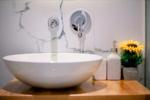 un lavabo blanco en una mesa de madera con flores en Hotel Olsi en Sarandë