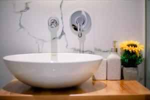 a white bowl sink on a wooden table with flowers at Hotel Olsi in Sarandë