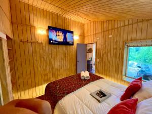 a bedroom with a bed with a tv on the wall at Stillner Waldhaus in Puerto Varas