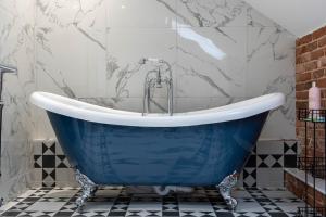 a blue tub in a bathroom with black and white tiles at 89 The Merchants- Chic Aparthotel by The House of Danu in Edinburgh