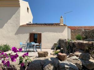 eine Terrasse mit einem Tisch und Stühlen vor einem Haus in der Unterkunft Stazzu nuraghe Mannucciu in Rena Majore