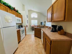 cocina con armarios de madera y nevera blanca en Ezras Vacation Home at Southern Dunes, en Haines City