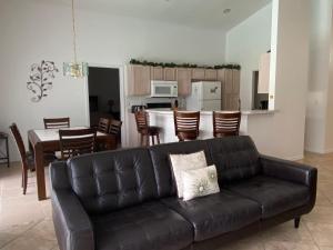 un soggiorno con un divano nero e una cucina di Kendra's Southern Dunes House a Haines City