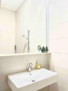 a white bathroom with a sink and a mirror at Centralize Stylish Loft Apartment Near MRT 市中心全景屋 in Singapore